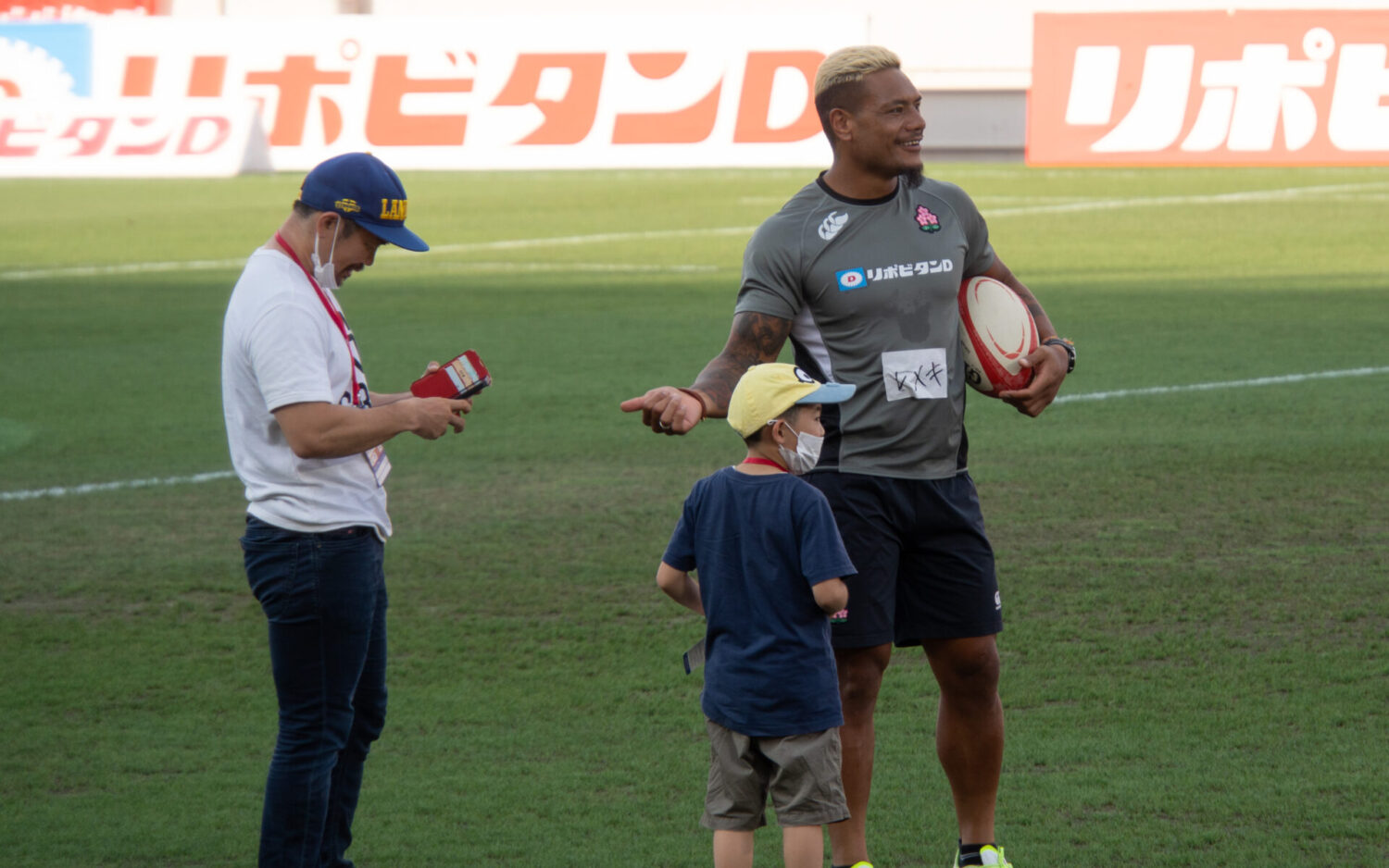 リポビタンD2023| JAPAN vs トンガ | 試合前の花園ラグビー場で日本代表候補のレメキロマノラヴァ選手と交流を深める元日本代表の田中史朗選手親子(NECグリーンロケッツ東葛)-Journal-ONE撮影