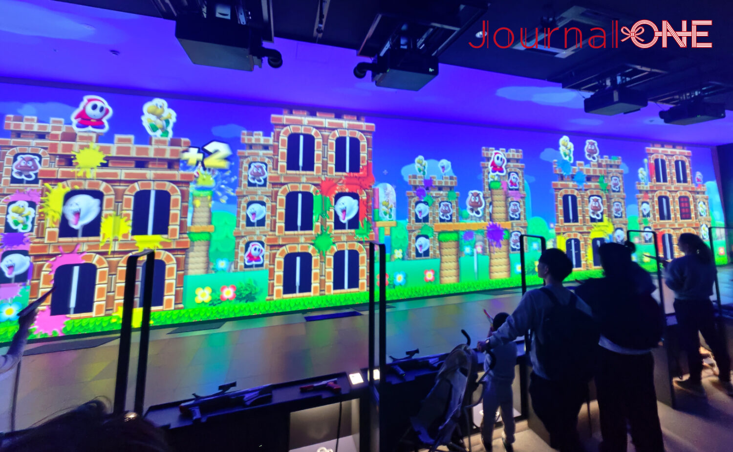 ニンテンドーミュージアムの体験エリアで巨大スクリーンのゲームに参加する来館者