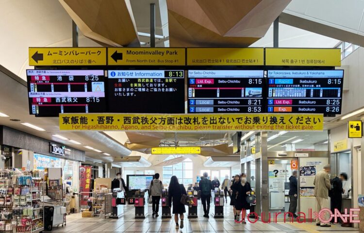 ムーミンバレーパークへの北口バスのりば案内が大きく掲げられた西武線飯能駅の改札口風景