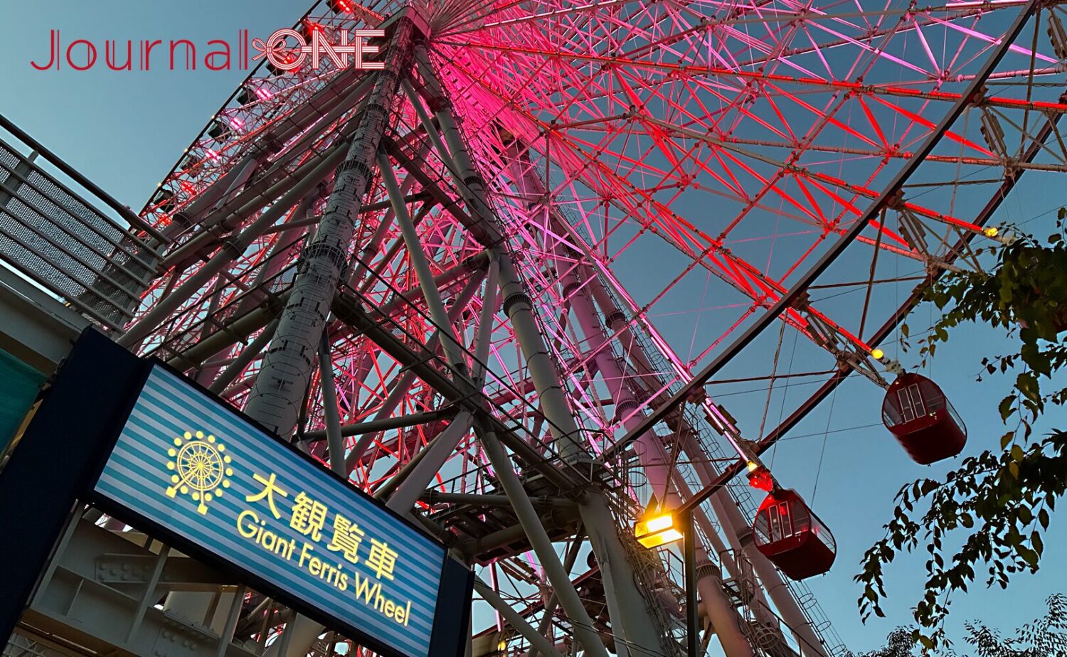 夜の天保山大観覧車がピンクに輝く様子。60台のゴンドラが夜空に弧を描いている