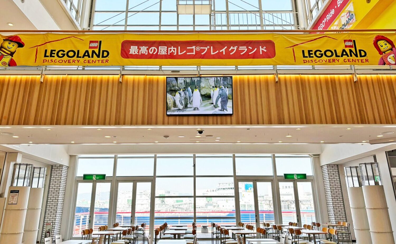 天保山マーケットプレースのフードコート。大きな窓の向こうに大阪港と船が見え、自然光が差し込む開放的な空間が広がっている。