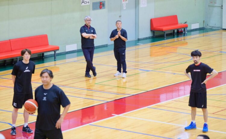 選手が練習に取り組む様子を見守りつつ会話をする桶谷大HCと佐藤賢次GM-永塚和志撮影