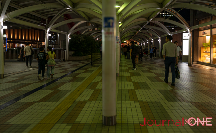 千里中央駅からせんちゅうパルへ続く歩行者デッキ。夜の回廊を多くの人が行き交う。