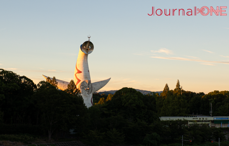 夕陽に照らされた太陽の塔。万博記念公園の深い緑の向こうに白い塔が浮かび上がる。